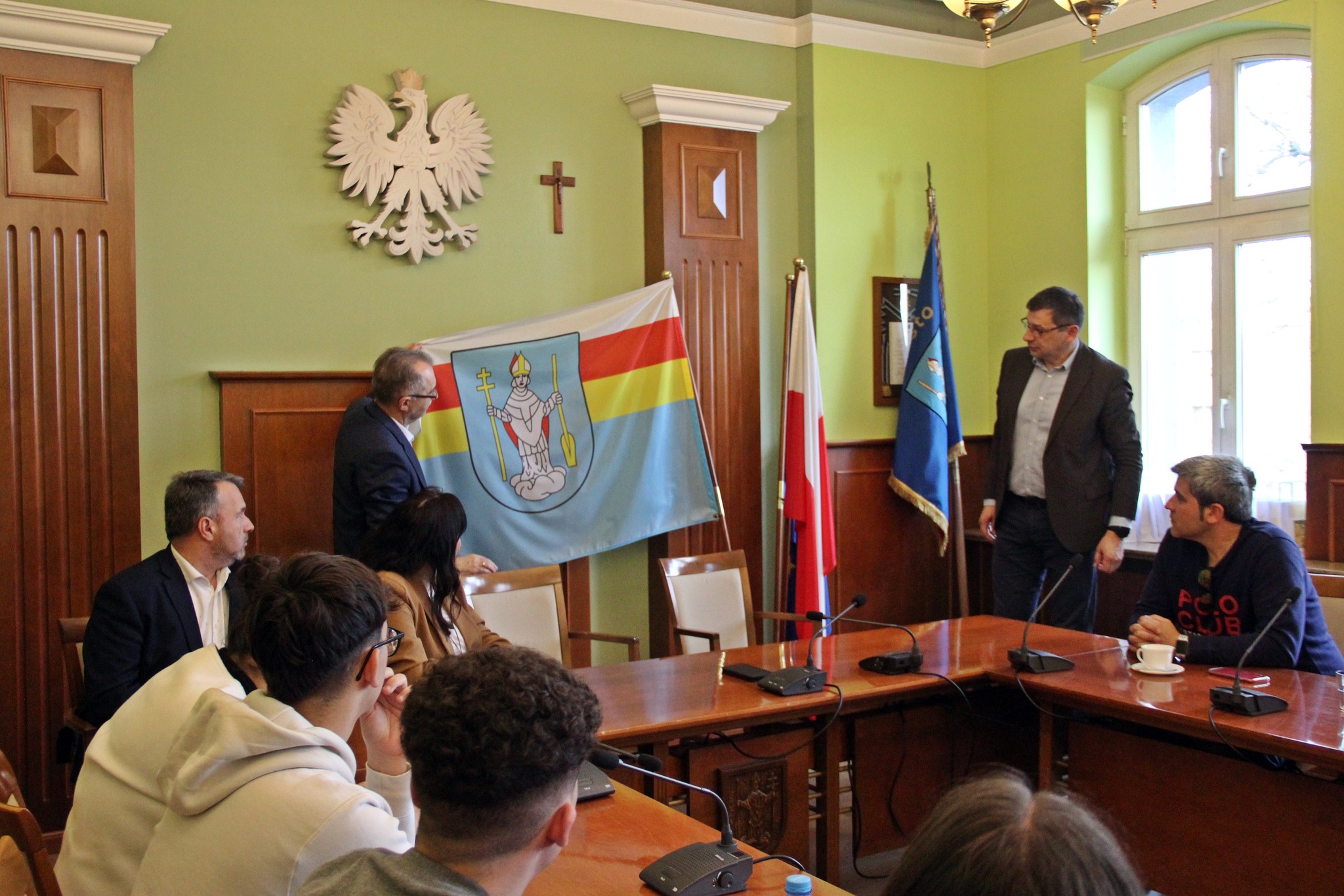 Przedstawiciel Urzędu pokazuje flagę Urzędu Miasta Radzionków.