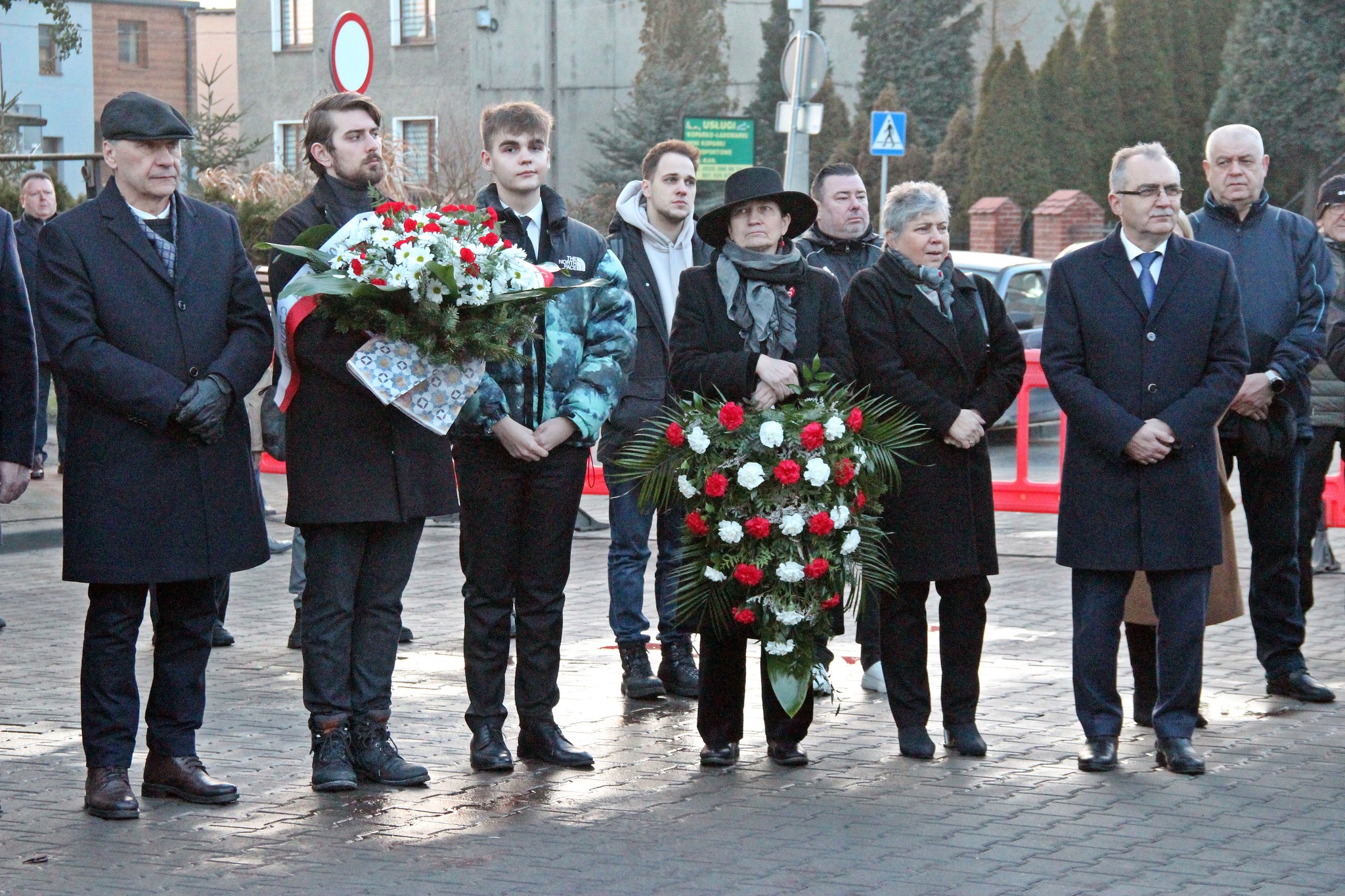 Uczestnicy wydarzenia stoją z wieńcami