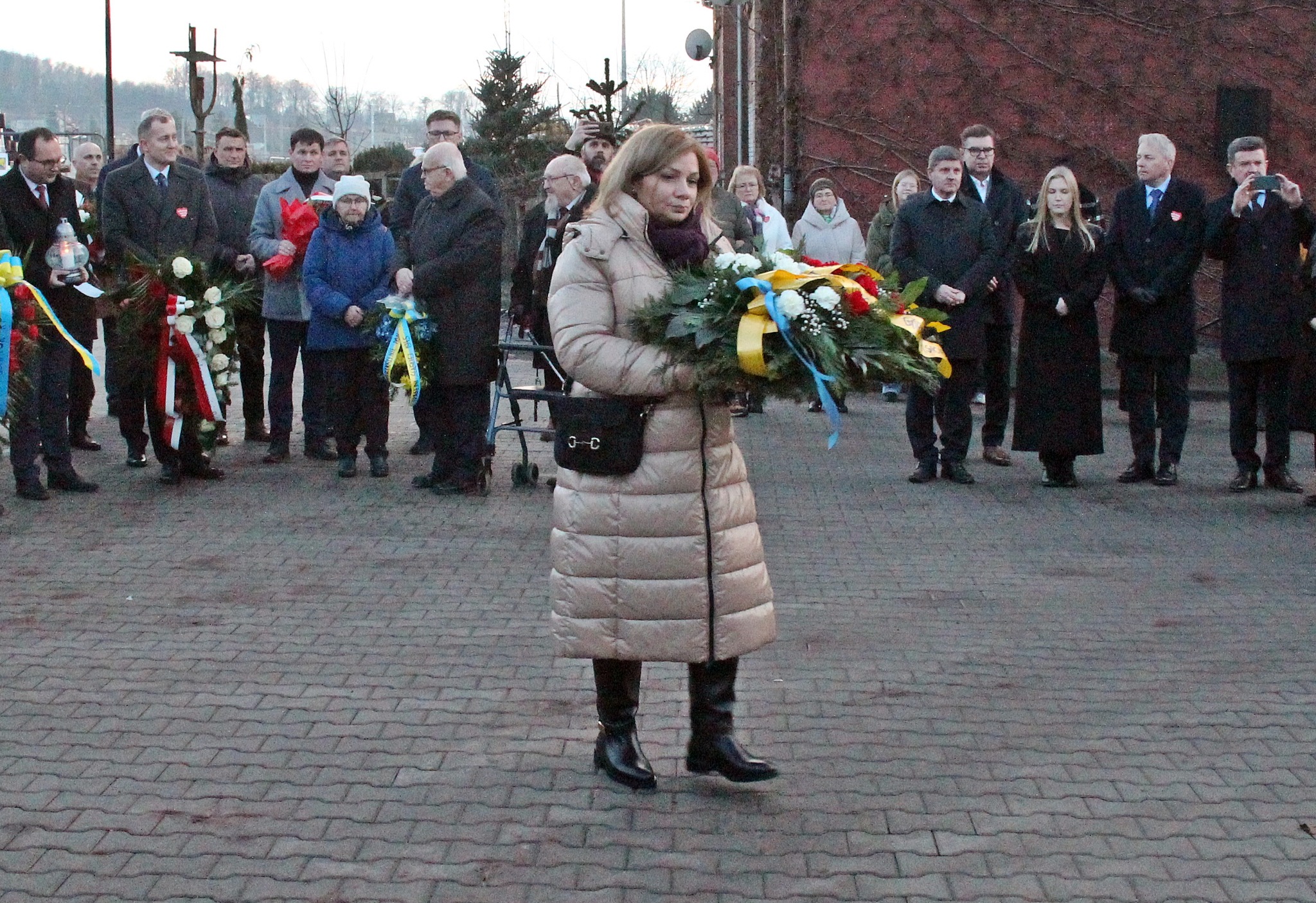 Pani podchodzi z wieńcem do tablicy pamiątkowej