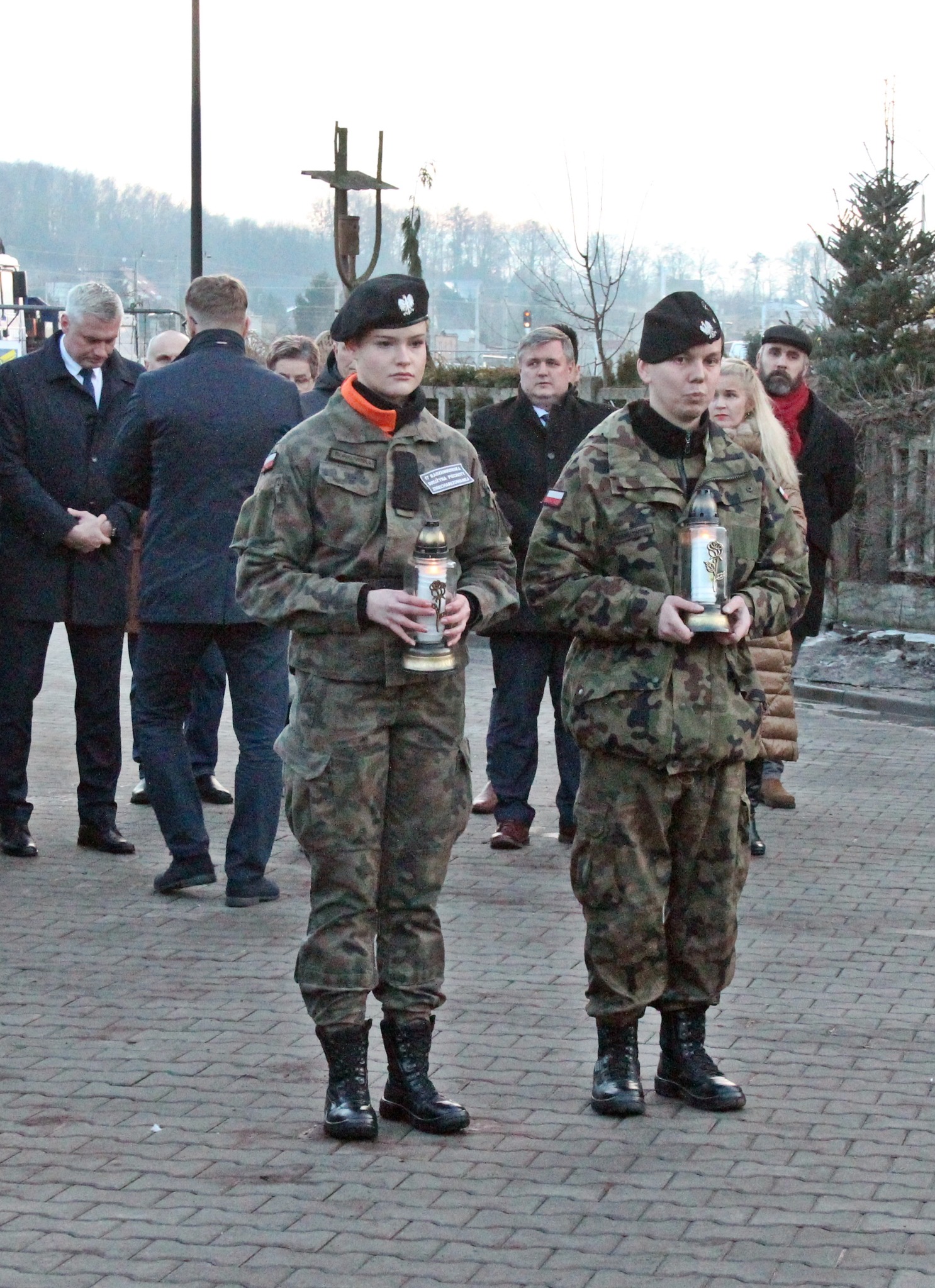 Dwie umundurowane kobiety stoją ze zniczami